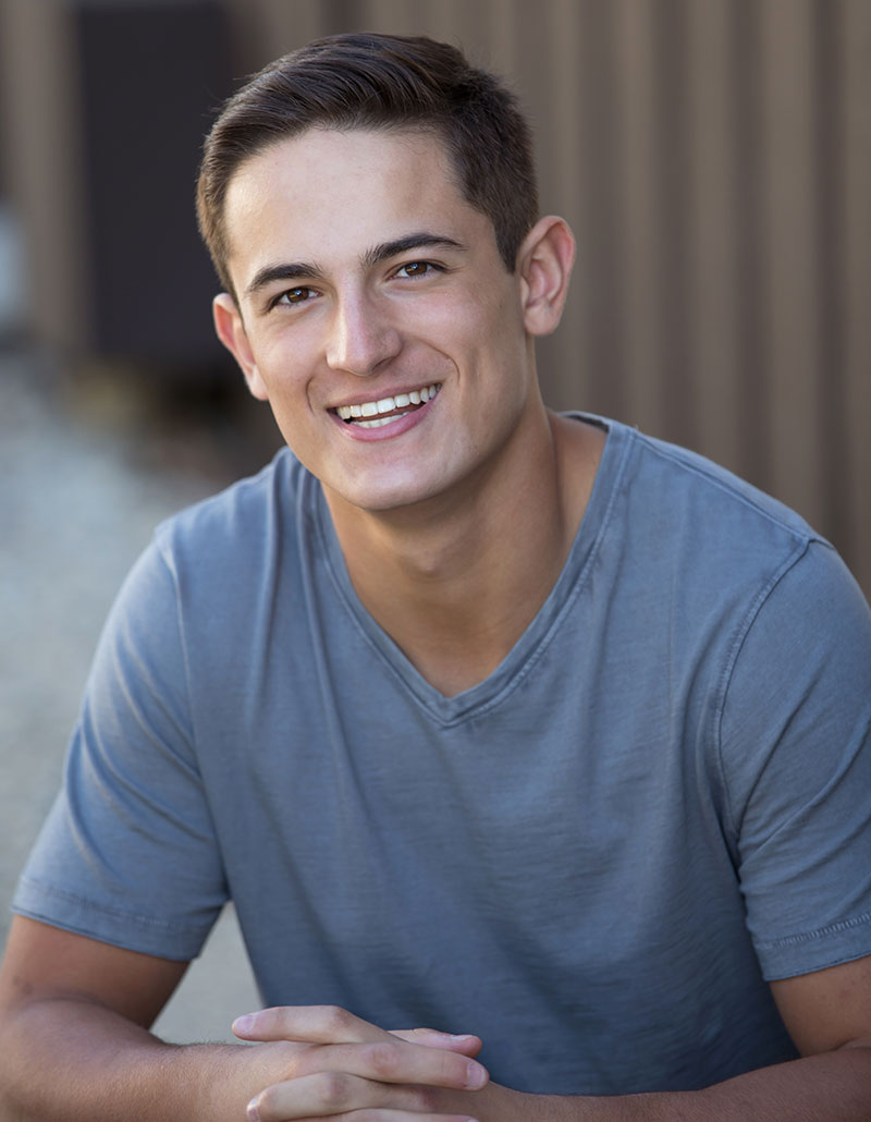 young man in grey shirt smiling happily